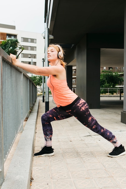 Mujer deportiva estirando en entorno urbano