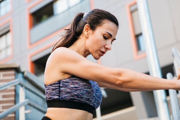 Mujer deportiva estirando en entorno urbano