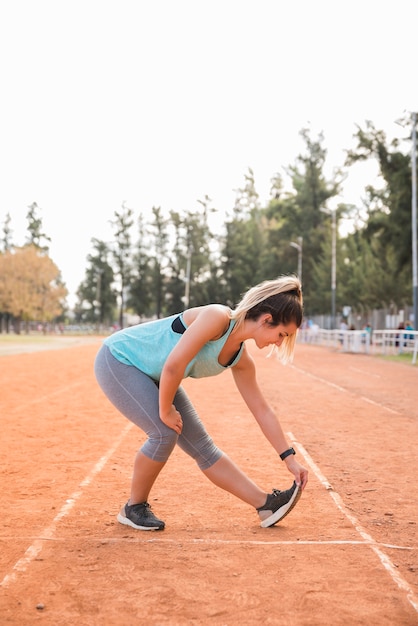 Foto gratuita mujer deportiva estirando en pista de estadio