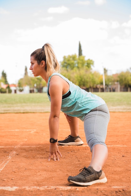 Mujer deportiva estirando en pista de estadio