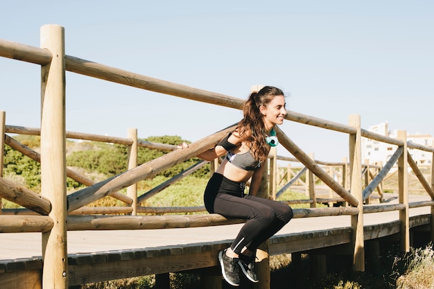 Mujer deportiva estirando en valla