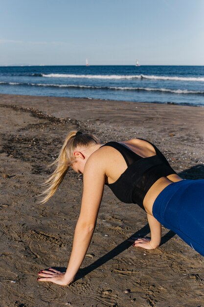 Mujer deportiva haciendo lagartijas en la playa