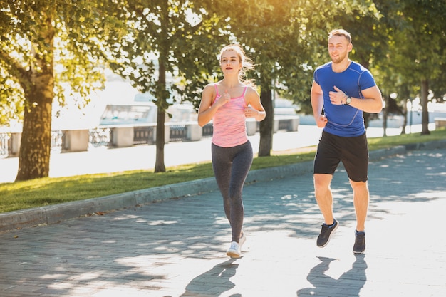 La mujer deportiva y el hombre corriendo en el parque a la luz del amanecer