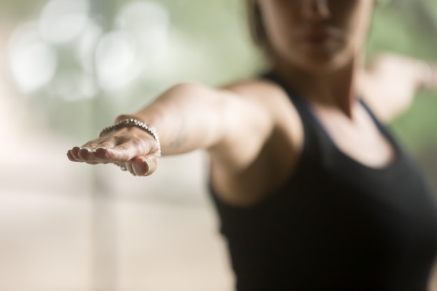 Mujer deportiva joven en la actitud del guerrero dos, fondo del estudio