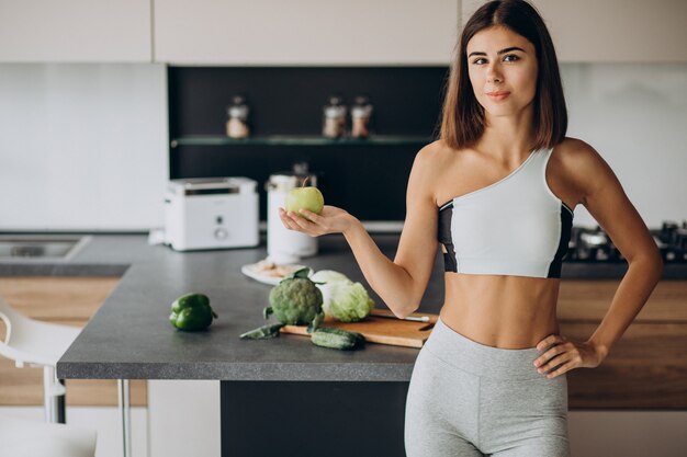 Mujer deportiva con manzana en la cocina