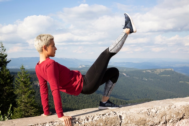 Mujer deportiva con pelo corto que se extiende en la naturaleza