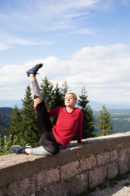 Mujer deportiva que se extiende en la naturaleza