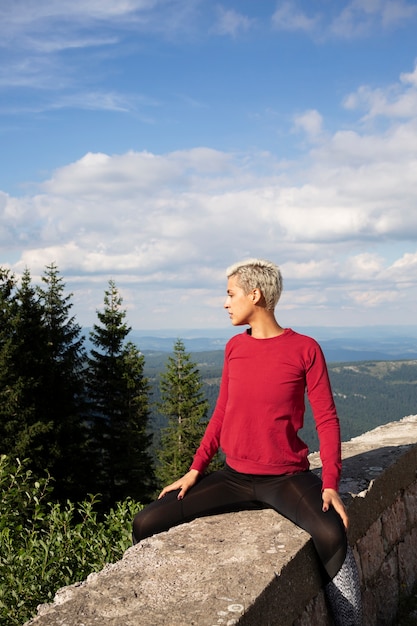 Mujer deportiva que se extiende en la naturaleza