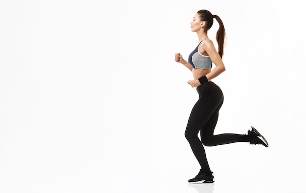 Mujer deportiva en ropa deportiva entrenamiento corriendo en blanco.