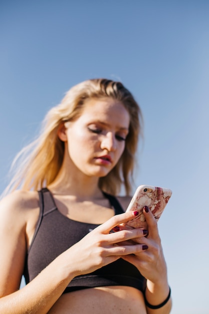 Mujer deportiva con smartphone en la playa