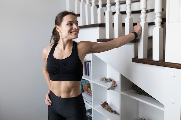 Mujer deportiva sonriente posando junto a las escaleras