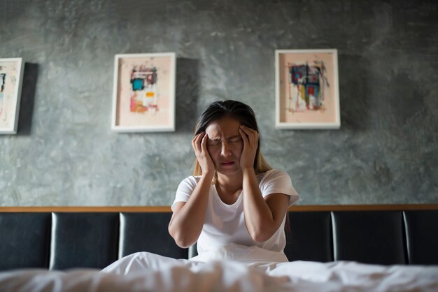 Mujer deprimida con dolor de cabeza mano sosteniendo su cabeza en la cama