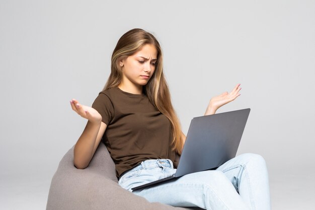 Mujer deprimida y frustrada que trabaja con la computadora portátil desesperada en el trabajo aislado en la pared blanca. Depresión