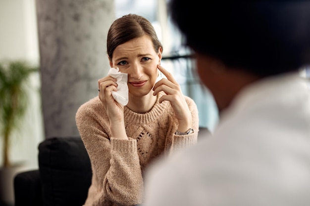 Mujer deprimida llorando mientras habla de sus problemas durante la sesión de psicoterapia