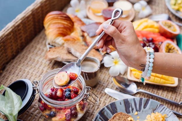 Mujer desayunando tropical saludable en villa en mesa flotante