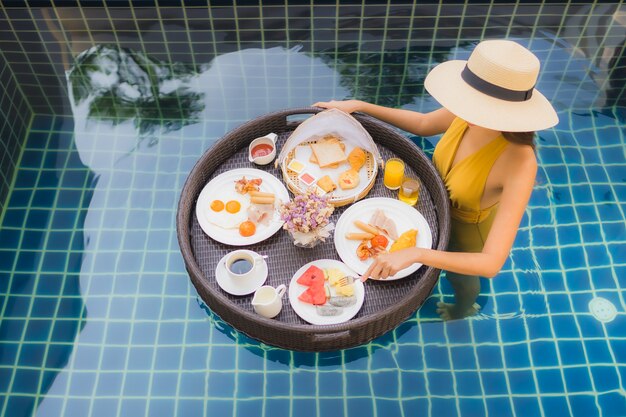 mujer con desayuno flotando alrededor de la piscina