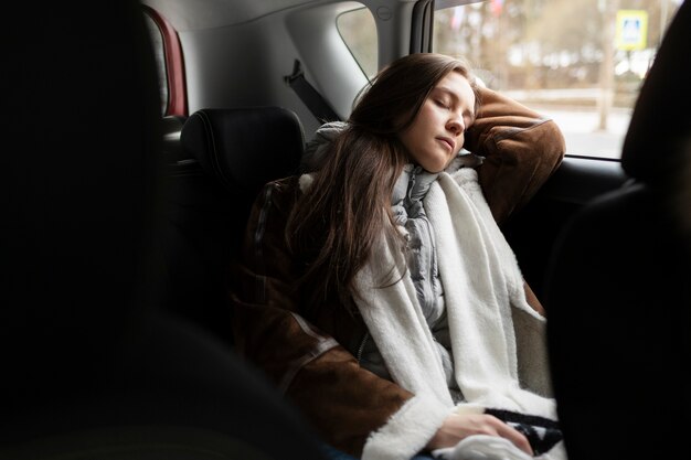Mujer descansando en el coche durante un viaje por carretera en invierno