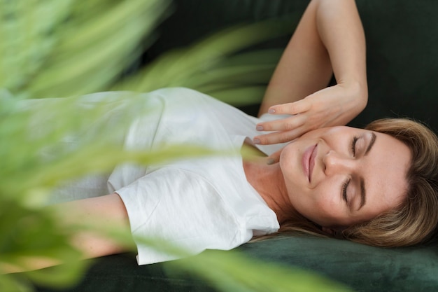 Mujer descansando en el sofá y planta borrosa