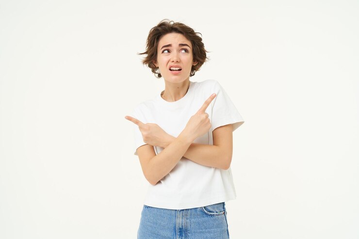 Foto gratuito una mujer desconcertada hace una elección, señala con los dedos a izquierda y derecha y decide confundida qué elegir.