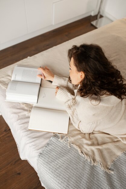Foto gratuita mujer desconectando digital en casa leyendo un libro en la cama