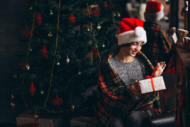 Mujer desempaquetando regalos por arbol de navidad