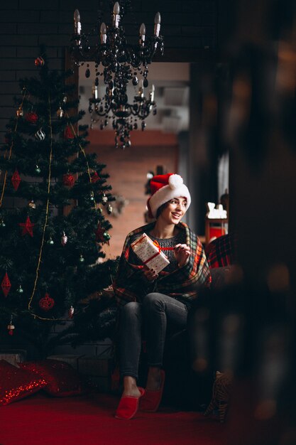 Mujer desempaquetando regalos por arbol de navidad