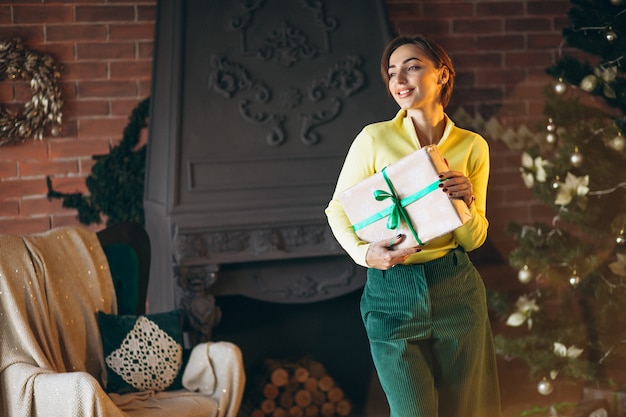 Mujer desempaquetando regalos por arbol de navidad