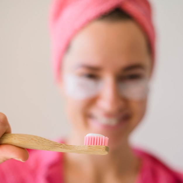 Mujer desenfocada con parches en los ojos con cepillo de dientes