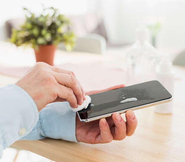 Mujer desinfectando su teléfono en casa