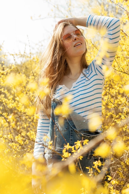 Mujer despreocupada con gafas de sol posando en campo de flores