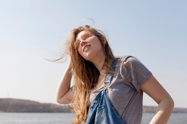 Mujer despreocupada posando junto al lago con gafas de sol