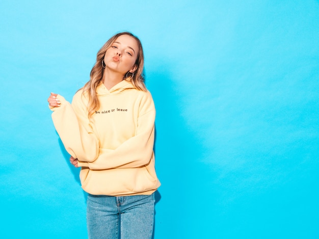 mujer despreocupada posando junto a la pared azul en studio