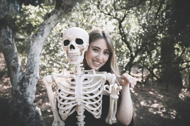 Mujer detrás del esqueleto con la mano que levanta