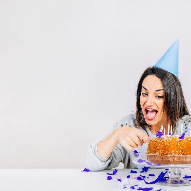 Mujer detrás de tarta de cumpleaños y espacio a la izquierda