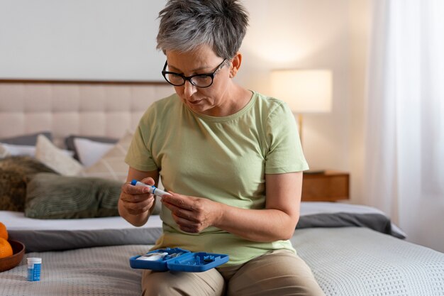 Mujer diabética de tiro medio comprobando su nivel de glucosa