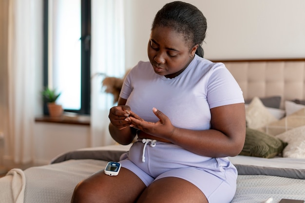 Mujer diabética de tiro medio comprobando su nivel de glucosa