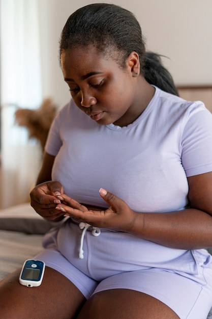 Mujer diabética de tiro medio comprobando su nivel de glucosa