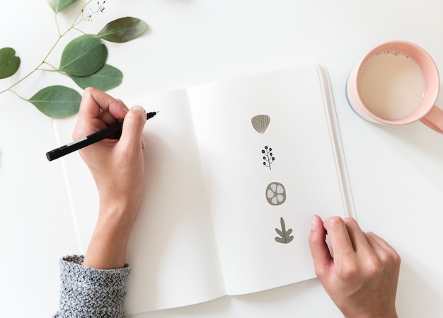 Mujer dibujando elementos de doodle en un cuaderno