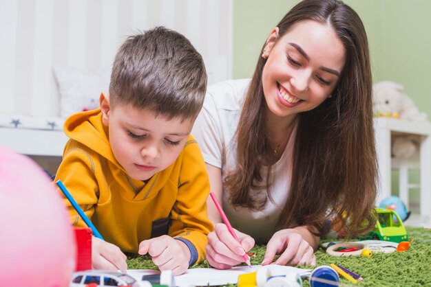 Mujer dibujando lápices con hijo