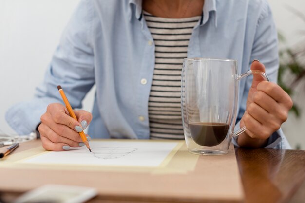 Mujer dibujando y sosteniendo la taza de café