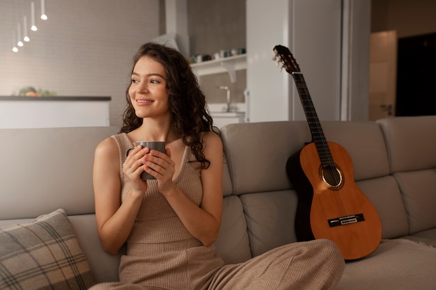 Mujer digital desconectando en casa con guitarra