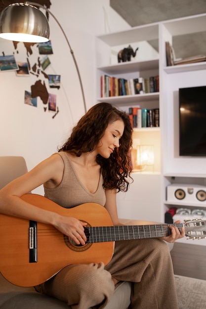 Mujer digital desconectando en casa con guitarra