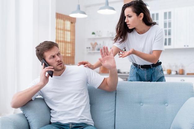 Mujer discutiendo con su novio mientras él está hablando por teléfono