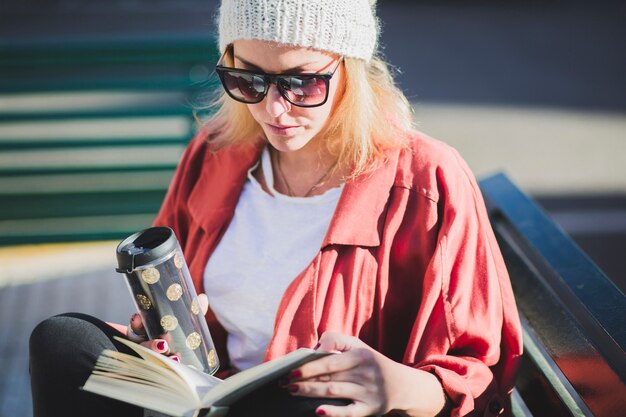 Mujer disfrutando de bebida caliente y libro