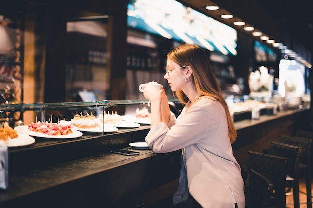 Mujer disfrutando de una bebida en el mostrador de la cafetería