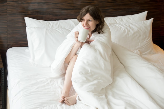 Mujer disfrutando de un café bajo la manta