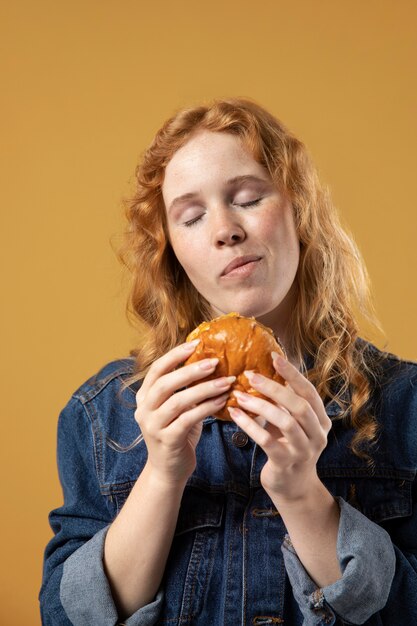 Mujer disfrutando comiendo una hamburguesa