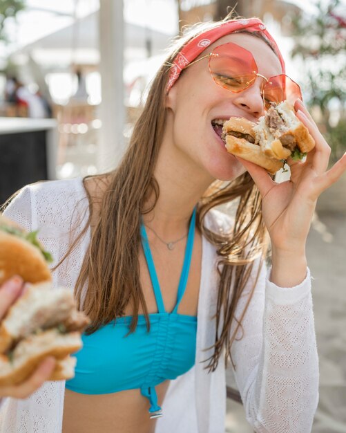 Mujer disfrutando de una hamburguesa en la playa