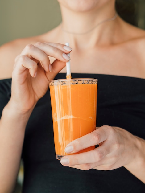 Mujer disfrutando de jugo de zanahoria fresco