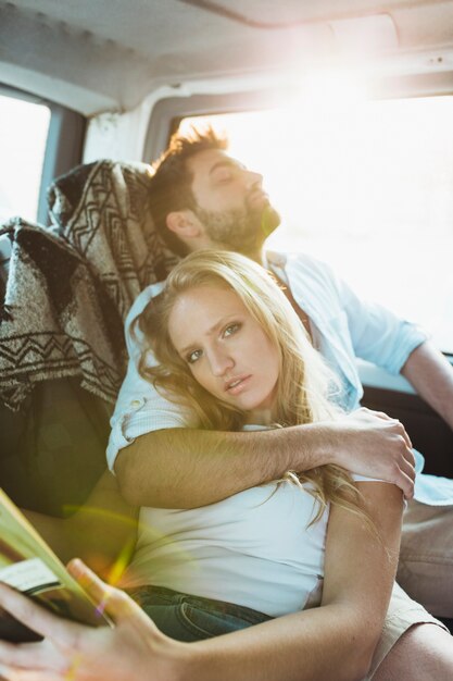 Mujer disfrutando de leer cerca de hombre dormido